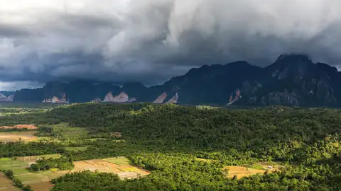 Imagem ilustrativa: Montanhas sob nuvens escuras e campos
