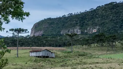 Imagem ilustrativa: Campo com montanha e cabana antiga