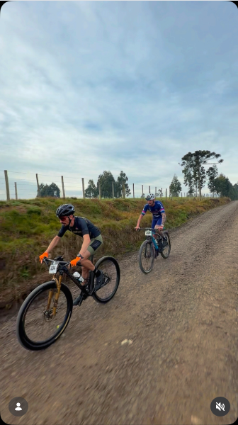 Dois ciclistas pedalam lado a lado por estrada de cascalho sob céu nublado, durante a 2ª etapa do Circuito Serrano de MTB